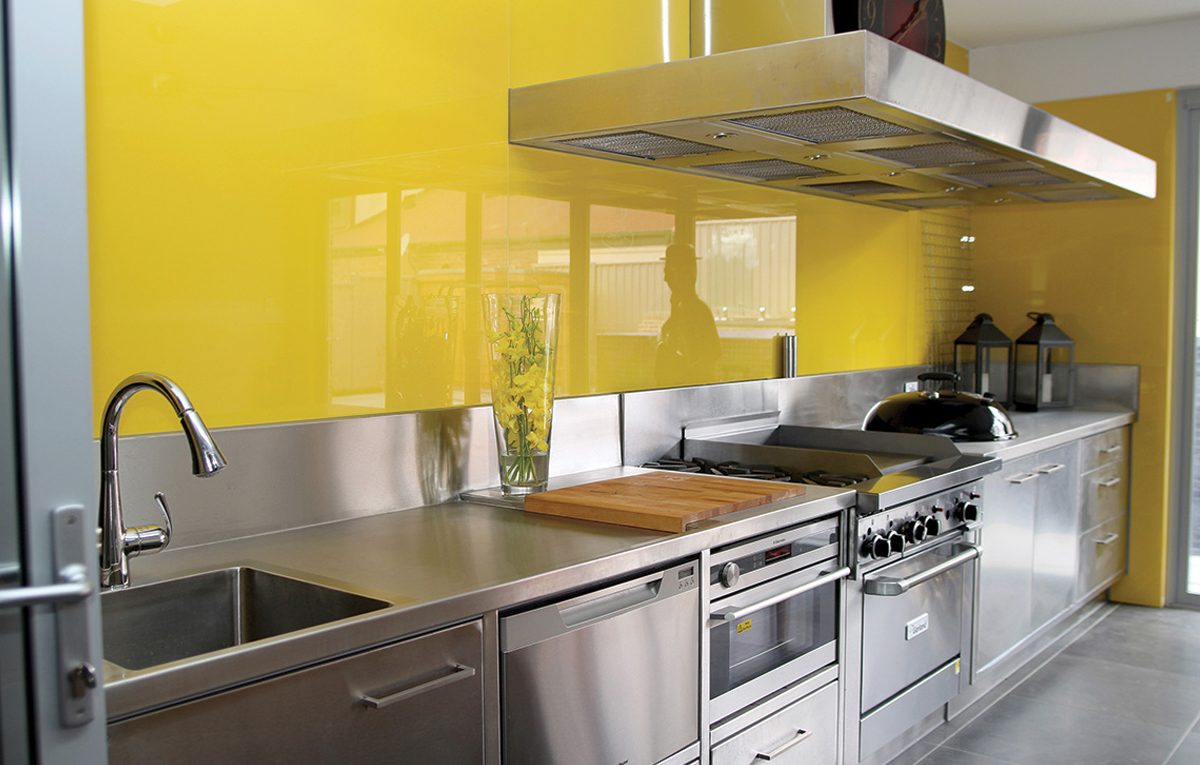 Yellow glass splashback in kitchen.
